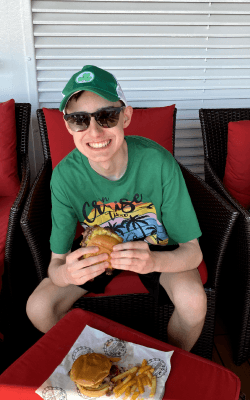 Nathan Parker eating a Guy's Burger on the 2024 Carnival Vista.